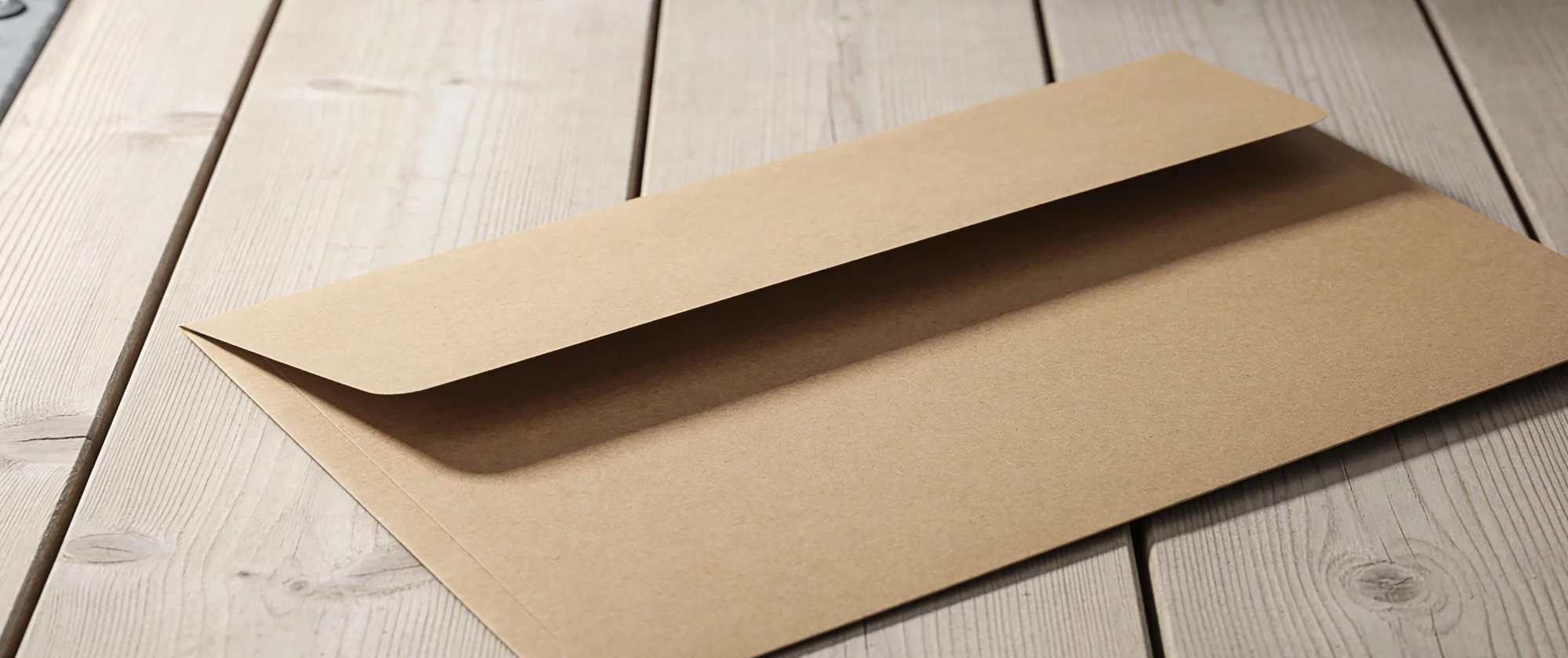 Briefumschlag ohne Schrift auf hellen Holzdielen